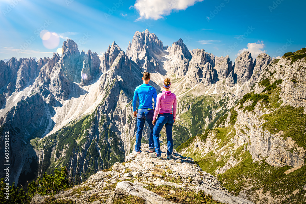 Athletic young couple enjoys epic view on Cadini di Misurina mountain range in the morning. Tre Cime, Dolomites, South Tirol, Italy, Europe.