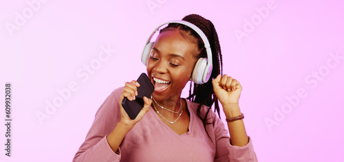 Sing, dance and black woman with headphones music microphone isolated on a studio background. Fun, happy and funky African girl listening to audio, radio or songs while singing and dancing on a backd