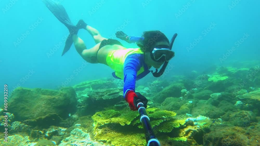 slow motion of asian female bikini girl wearing snorkel and long fins diving underwater with green table corals shining from sunlight hue ray reflection light during day time in ocean slow motion of asian female bikini girl wearing snorkel and long fins diving underwater with green table corals shining from sunlight hue ray reflection light during day time in ocean