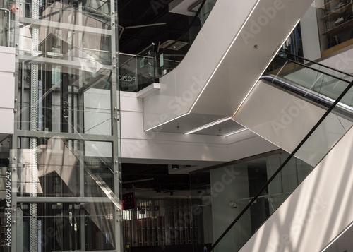 Modern glass elevator and escalator in a shopping mall. Empty mall.
