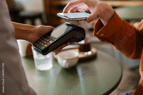 Slika na platnu Close up man paying with mobile phone using contactless terminal