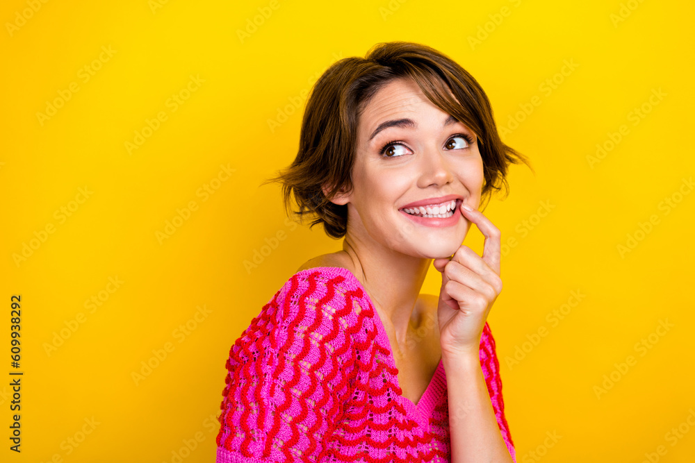 Portrait of pleasant adorable woman short haircut wear pink knit top look empty space finger on lips isolated on yellow color background Portrait of pleasant adorable woman short haircut wear pink knit top look empty space finger on lips isolated on yellow color background
