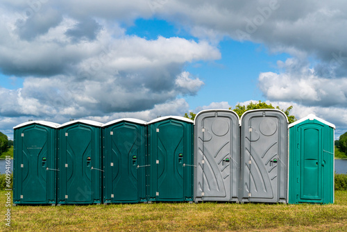 Row of plastic portable toilets at an outdoor event