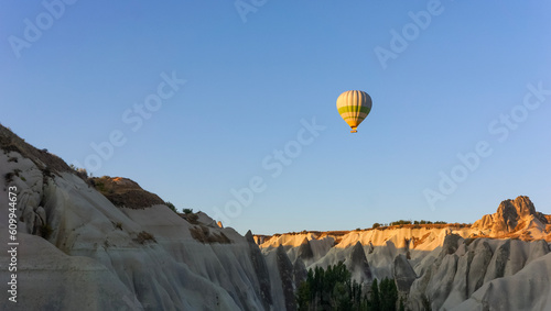 Hot air balloon flying in sunset sky over mountains, Cappadocia, Turkey