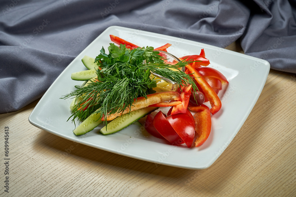 A plate with fresh vegetables, tomatoes, peppers and cucumbers. A plate with fresh vegetables, tomatoes, peppers and cucumbers.