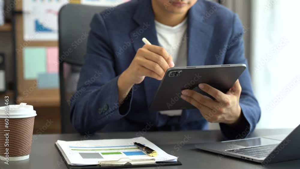 Businessman using a tablet to analysis graph company financial in home office. Businessman using a tablet to analysis graph company financial in home office.