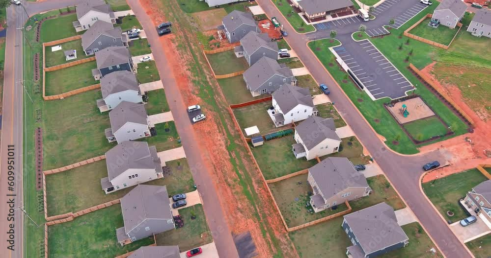 Aerial view showcases an expansive unfinished subdivision housing complex, with rows of houses in various stages of construction Aerial view showcases an expansive unfinished subdivision housing complex, with rows of houses in various stages of construction