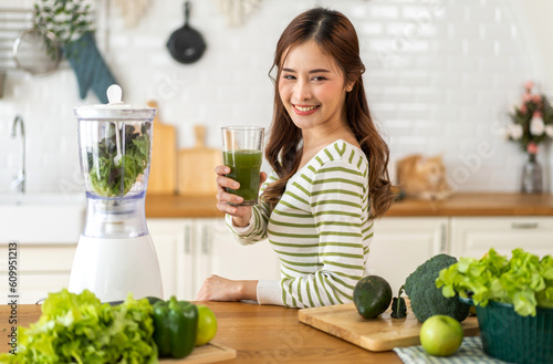 Portrait of beauty healthy asian woman making green vegetables detox cleanse and green fruit smoothie with blender.young girl drinking glass of smoothie, fiber, chlorophyll in kitchen.Diet, healthy