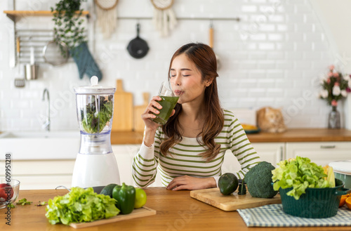 Portrait of beauty healthy asian woman making green vegetables detox cleanse and green fruit smoothie with blender.young girl drinking glass of smoothie, fiber, chlorophyll in kitchen.Diet, healthy
