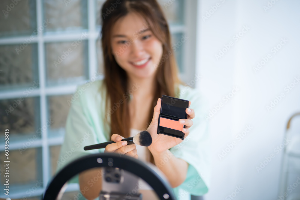 Young Asian girl makeup artist Professional Woman blogger vlogger is showing cosmetics products with recording video beautiful asian girl video online marketing.