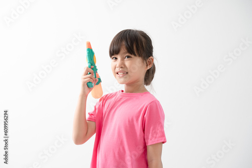Happy Songkran Day, Asian kid girl hold water gun, Thai child funny hold toy water pistol and smile, isolated on white background, Thailand Songkran festival national culture concept
