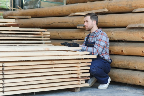 Carpenter in uniform check boards on sawmill