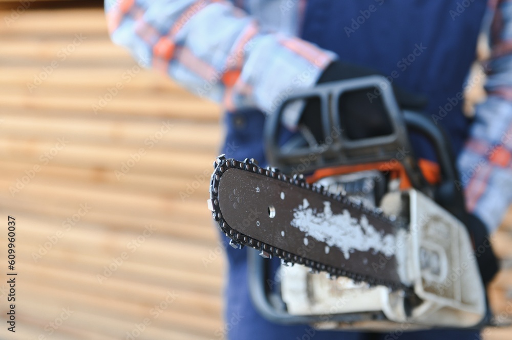 Carpenter with a saw in his hands stands on a background of cut wooden boards. Carpenter with a saw in his hands stands on a background of cut wooden boards.
