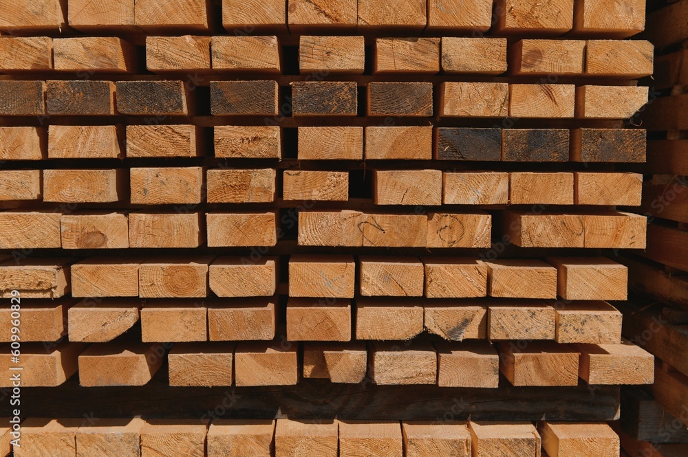 Fototapeta premium Stack of lumber of a wooden board from a tree, close-up, background. Wooden boards at the sawmill, carpentry workshop. Sawing and air drying of wood. Woodworking industry. Wooden boards