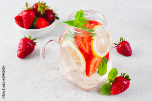 Strawberry Infused Water, Refreshing Cocktail, Lemonade, Detox Iced Drink with Fresh Strawberry, Lemon and Mint on Bright Background