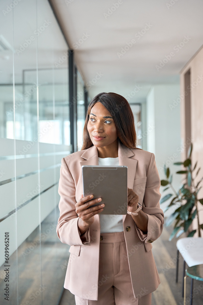 © insta_photos - Young busy professional African American business woman company manager sales executive wearing suit holding tab using digital tablet computer standing in office looking away thinking, vertical. © insta_photos - Young busy professional African American business woman company manager sales executive wearing suit holding tab using digital tablet computer standing in office looking away thinking, vertical.