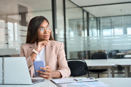 Wallpaper Mural Young professional African American business woman executive manager holding cellphone using mobile looking away at copy space thinking on cell phone tech solutions sitting at desk working in office. Torontodigital.ca