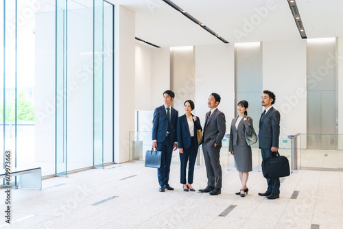 オフィスビルのロビーで空を見上げるビジネスパーソンのグループ photo