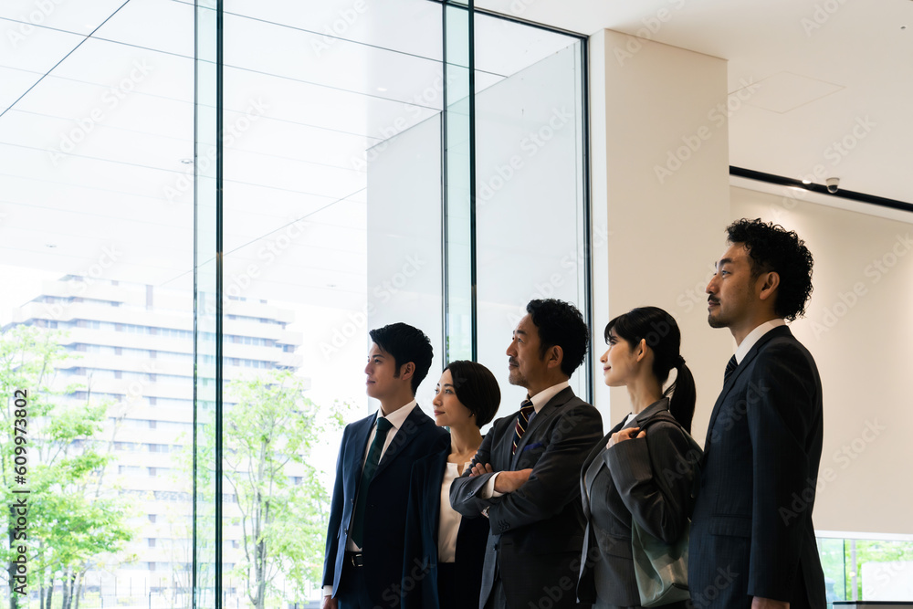 オフィスビルのロビーで空を見上げるビジネスパーソンのグループ