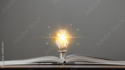 Glowing light bulb with creativity twinkling lights on a book. Ideas for inspiration from reading. Innovation concept of self-learning, education knowledge, technology, business, power of knowledge.