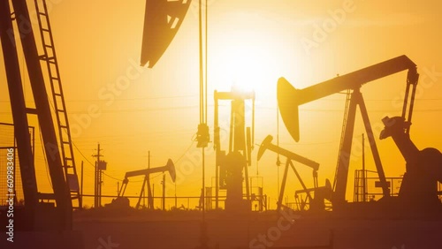 The sun rises behind a large oil field in California.