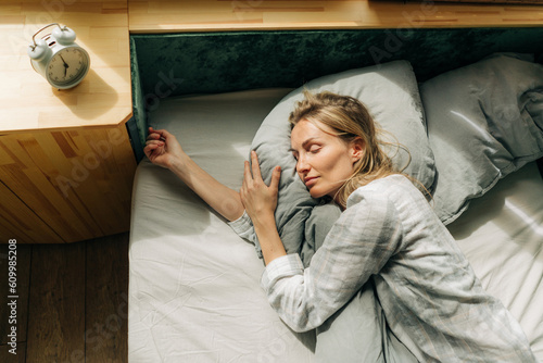 Obraz na plátne Lifestyle portrait of a woman in pajamas sleeping while lying in bed  blissfully