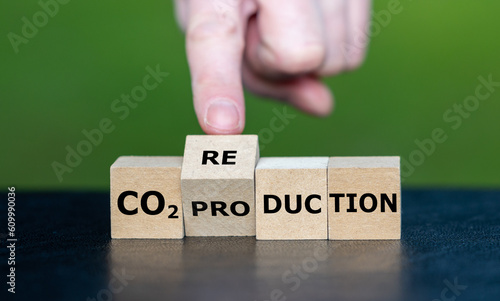 Hand turns wooden cube and changes the expression 'CO2 production' to 'CO2 reduction'.