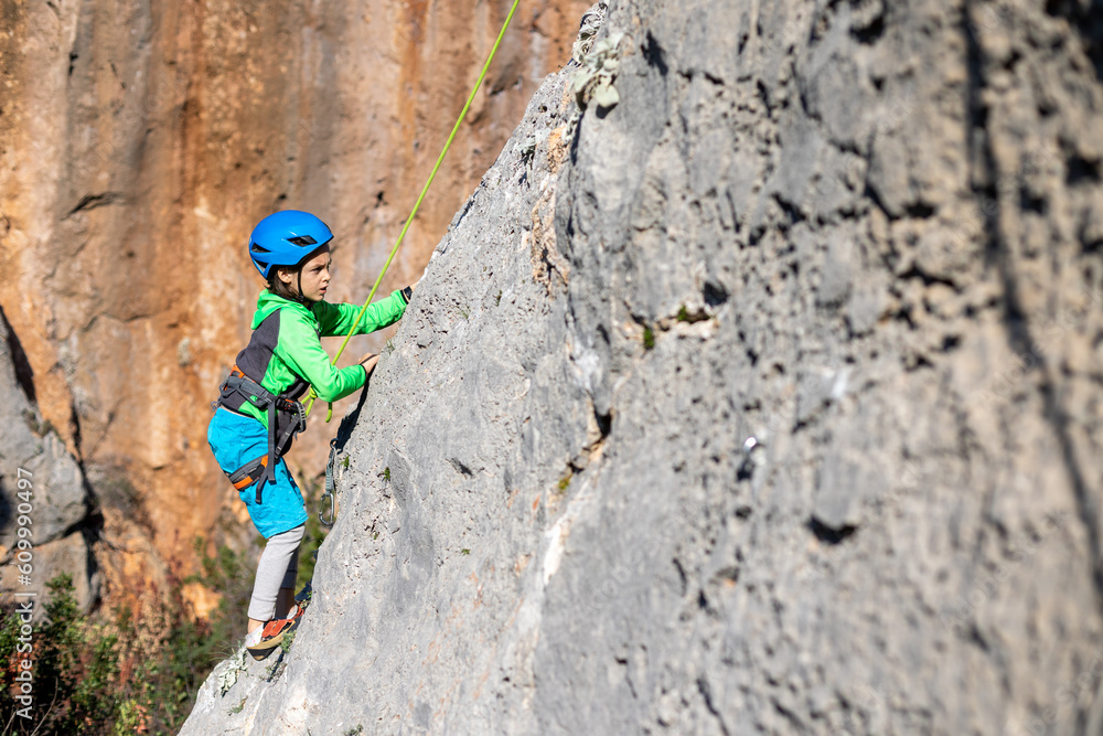 Child rock climber. The boy climbs the rock. The child is engaged in rock climbing on natural terrain. Sports kid spends time actively. Child rock climber. The boy climbs the rock. The child is engaged in rock climbing on natural terrain. Sports kid spends time actively.