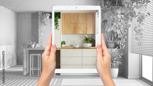 Hands holding tablet showing minimal kitchen, total blank project background, augmented reality concept, application to simulate furniture and interior design products