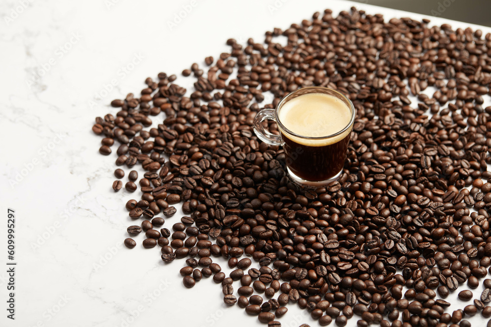 Cup of espresso coffee and coffee beans, on white marble table Cup of espresso coffee and coffee beans, on white marble table