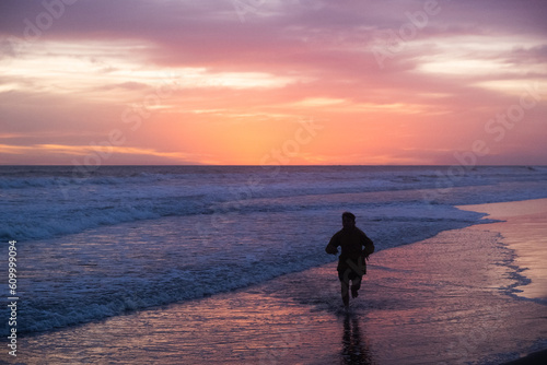 Silueta de niño corriendo en la playa durante el atardecer