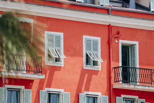 Fototapeta Naklejka Na Ścianę i Meble -  Bright red southern facades of Nice and typical windows with shutters, contrasting color