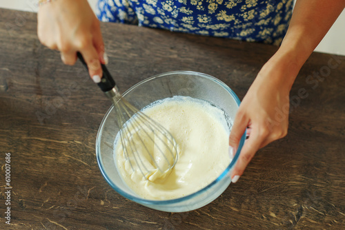 Quadro em tela Beautiful hands stir the dough with a black whisk in a deep transparent bowl