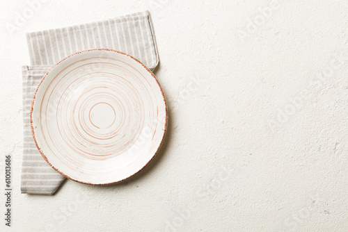 Photography Top view on colored background empty round white plate on tablecloth for food