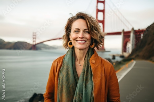 Portrait of a beautiful middle-aged woman smiling while standing in front of the Golden Gate Bridge, San Francisco, California, USA