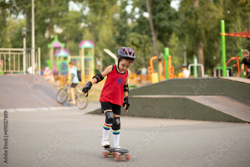 Cute kid girl child riding a skateboard in skatepark. Child performs tricks. Summer sport activity concept. Happy childhood.