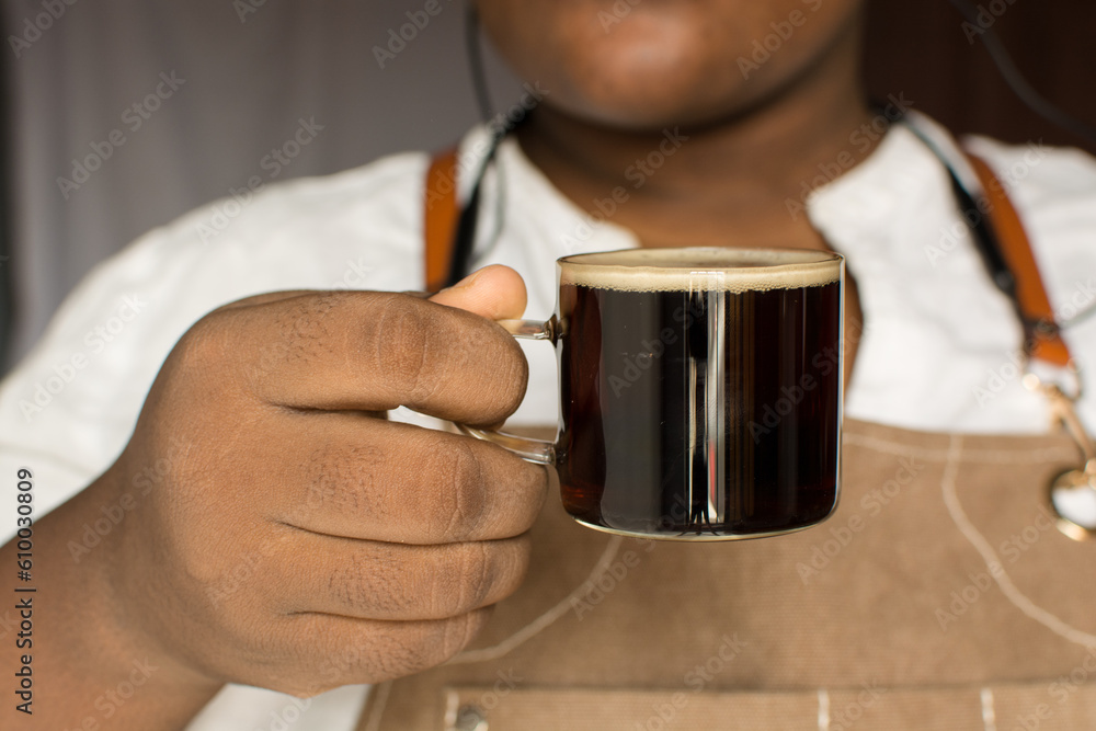 Barista holding a cup of espresso, Espresso in a glass cup, foamy top of coffee