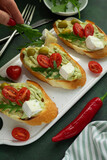 Bruschetta with guacamole, tomatoes, cheese, olives and greens
