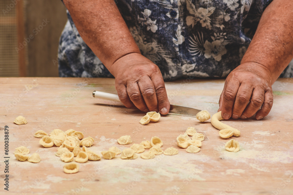 Local woman in the street of Bari old town making orecchiette or orecchietta, handmade pasta made with durum wheat and water typical of Puglia or Apulia, Italy, close up Local woman in the street of Bari old town making orecchiette or orecchietta, handmade pasta made with durum wheat and water typical of Puglia or Apulia, Italy, close up