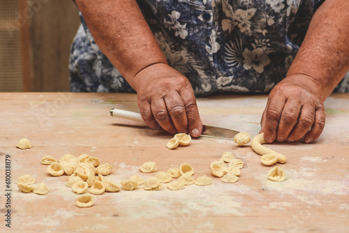 Local woman in the street of Bari old town making orecchiette or orecchietta, handmade pasta made with durum wheat and water typical of Puglia or Apulia, Italy, close up