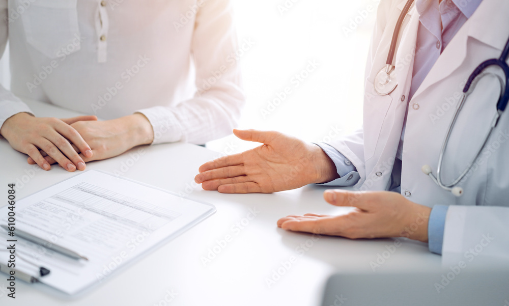 Doctor and patient discussing current health questions while sitting near of each other and using clipboard at the table in clinic, just hands closeup. Medicine concept. Doctor and patient discussing current health questions while sitting near of each other and using clipboard at the table in clinic, just hands closeup. Medicine concept.