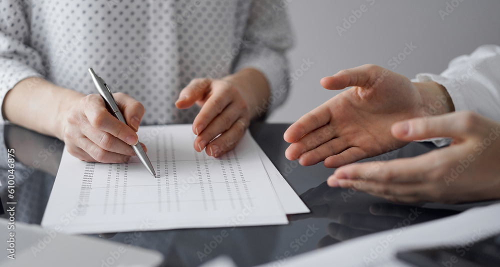 Woman accountant using a calculator and laptop computer while counting and discussing taxes with a client. Business audit and finance concepts. Woman accountant using a calculator and laptop computer while counting and discussing taxes with a client. Business audit and finance concepts.