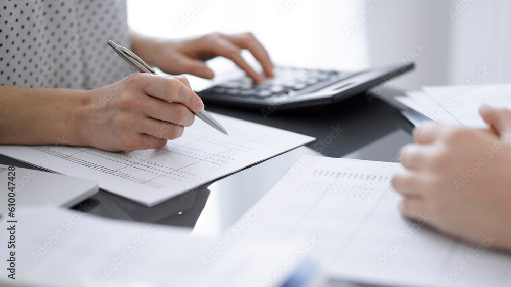 Woman accountant using a calculator and laptop computer while counting taxes for a client. Business audit concepts. Woman accountant using a calculator and laptop computer while counting taxes for a client. Business audit concepts.