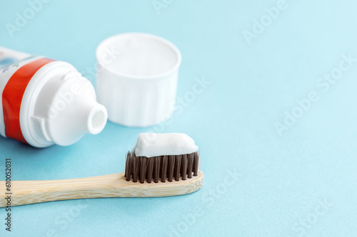 Toothbrush with toothpaste and white tube of toothpaste on blue background