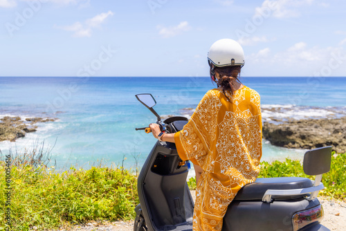 Woman ride a motor bike beside the sea, road trip concept
