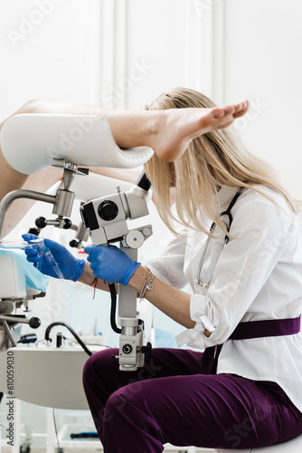 Gynecologist is looking in colposcope for detail examination of disease. Gynecologist does colposcopy procedure to closely examine cervix, vagina and vulva of girl in gynecology clinic. photo