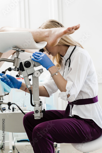 Gynecologist is looking in colposcope for detail examination of disease. Gynecologist does colposcopy procedure to closely examine cervix  vagina and vulva of girl in gynecology clinic.