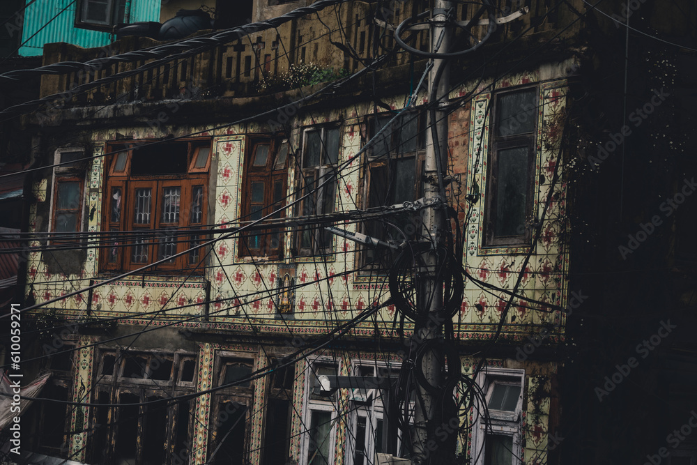Old abandoned building with beautiful tiles on the wall - Electric pole with a lot of wires in the foreground