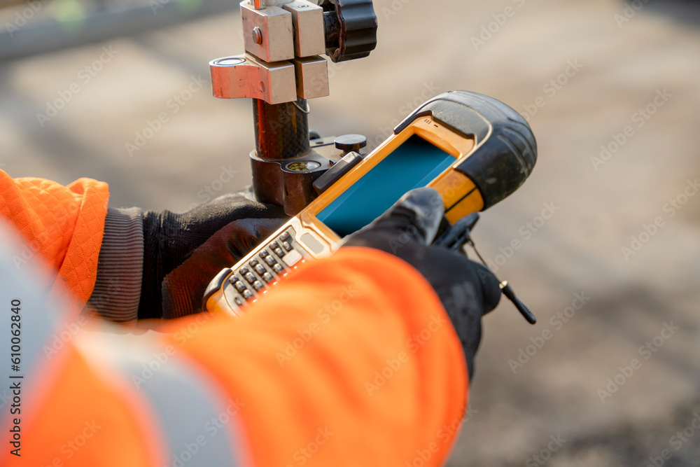 Site engineer operating his touch screen controller instrument during roadworks. Builder using