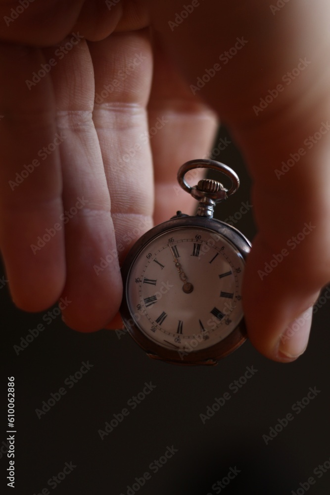 white hands holding a silver white pocket watch in black background white hands holding a silver white pocket watch in black background